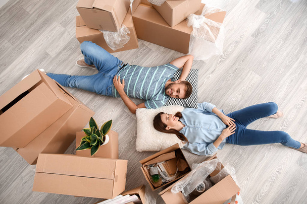 Happy young couple with belongings lying on floor in their new house - Фото, зображення