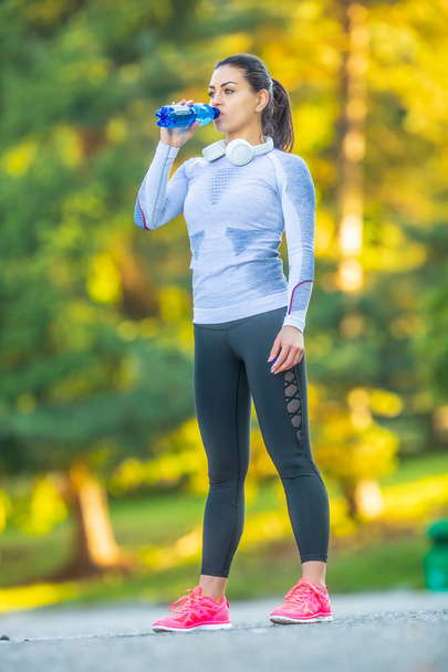 Młoda kobieta sportowiec napojów wody po treningu. - Zdjęcie, obraz