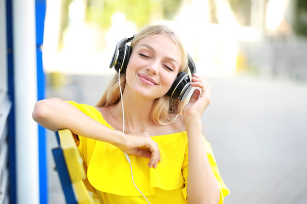 Mooie jonge vrouw luisteren aan muziek in openlucht - Foto, afbeelding