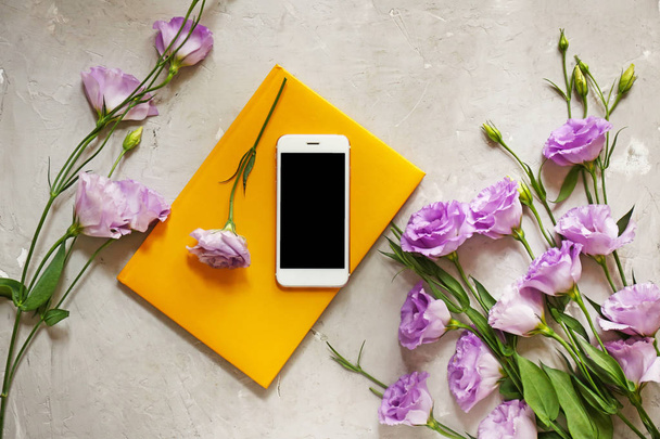 Modern mobile phone with flowers and notebook on grunge background - Fotó, kép