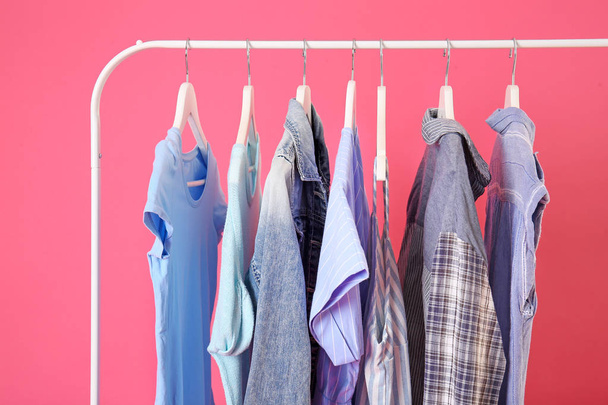 Rack with hanging clothes on color background - Photo, image