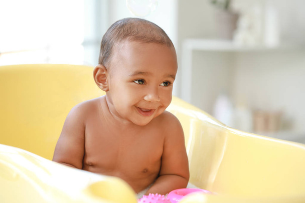 Pieni afroamerikkalainen vauva pesu kylpyammeessa kotona
 - Valokuva, kuva
