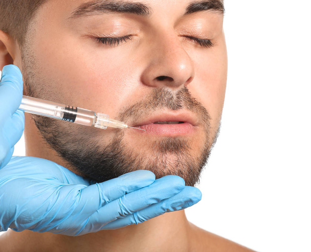 Handsome man receiving filler injection on white background, closeup - Foto, Bild