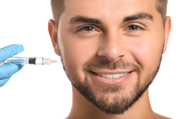 Handsome man receiving filler injection on white background - Фото, зображення