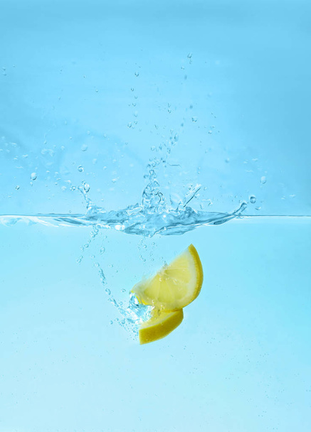 Wasser mit Zitronenscheiben vor blauem Hintergrund. erfrischendes Getränk - Foto, Bild