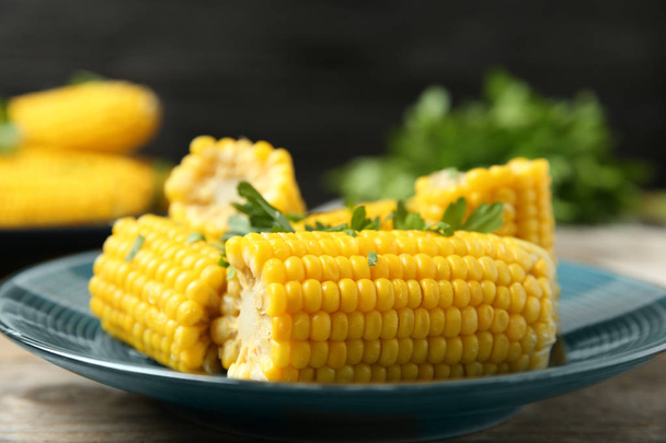 Plate of boiled corn cobs with parsley on wooden table, closeup - Photo, Image