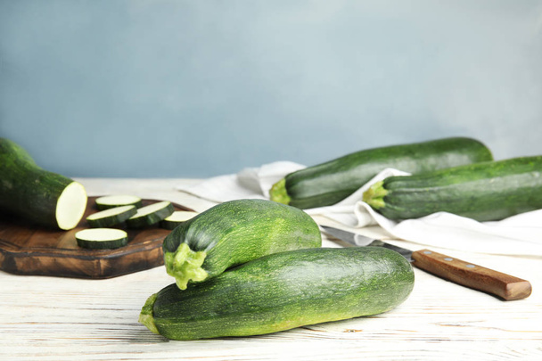 Fresh ripe green zucchinis on white wooden table against blue background, space for text - Φωτογραφία, εικόνα