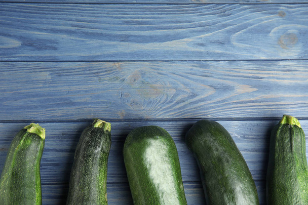 Fresh ripe green zucchinis on blue wooden table, flat lay. Space for text - Fotoğraf, Görsel