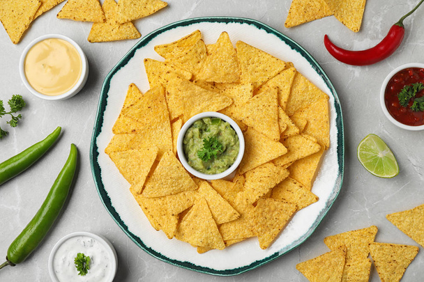 Mexican nacho chips with different sauces on grey marble background, flat lay - Foto, immagini