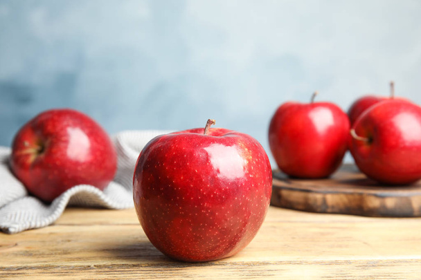 Ripe juicy red apples on wooden table against blue background - Фото, зображення