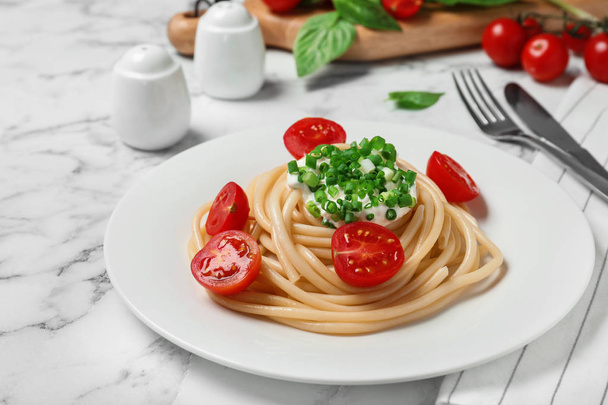 Delicious spaghetti with sour cream dressing on white marble table - Foto, Imagem