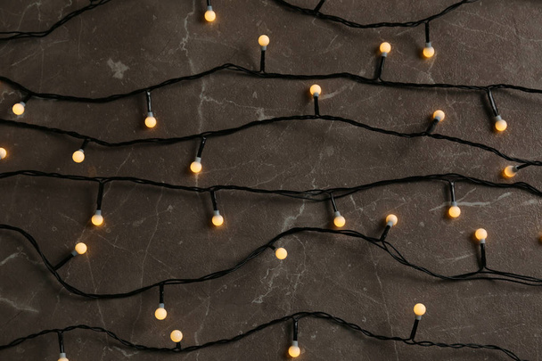 Glowing Christmas lights on grey marble background, top view - Zdjęcie, obraz
