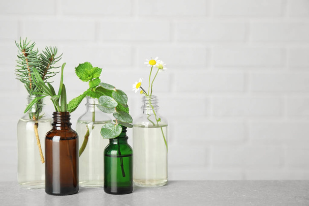 Bouteilles en verre de différentes huiles essentielles avec des plantes sur la table. Espace pour le texte
 - Photo, image