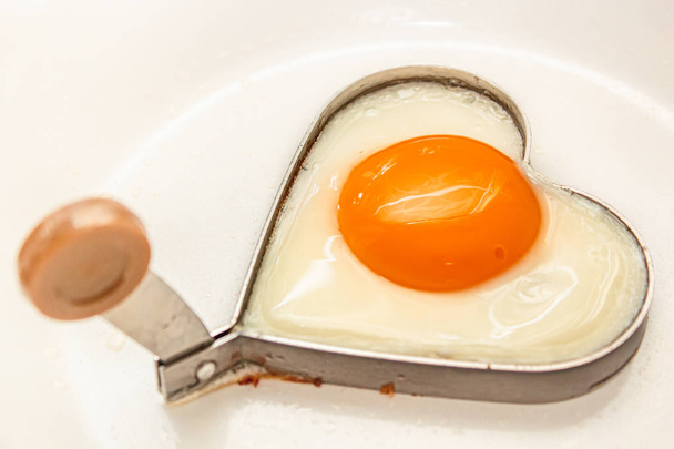 Fried eggs heart shape homemade meal on a frying pan.  - Fotó, kép