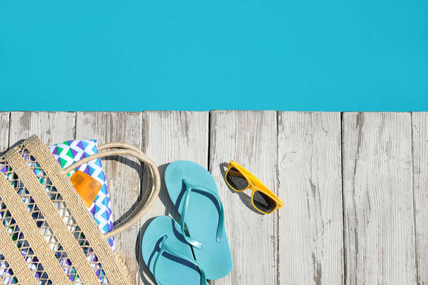 Beach accessories on wooden deck near outdoor swimming pool, flat lay. Space for text - Fotoğraf, Görsel