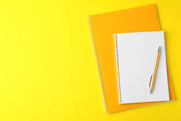 Notebooks and pen on yellow background, top view - Photo, image