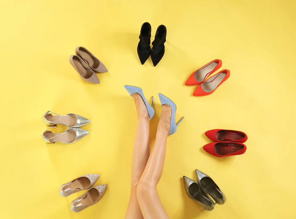 Woman and different high heel shoes on yellow background, top view - Foto, immagini