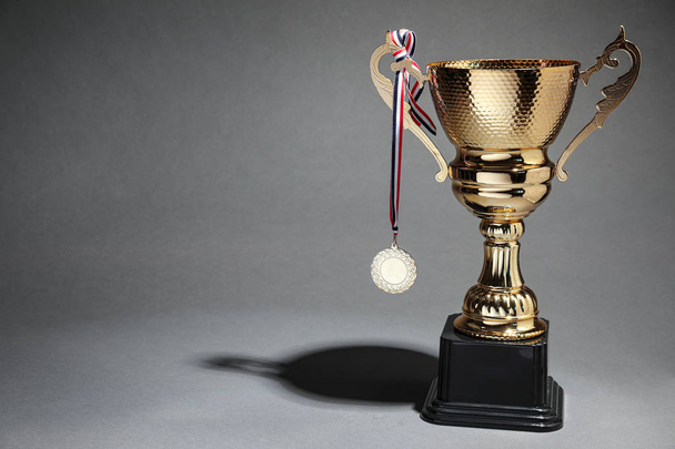 Golden trophy cup and medal on grey background. Space for text - Foto, immagini