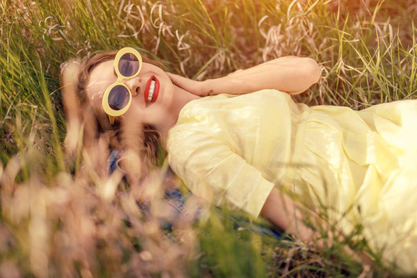 Стильная дама, отдыхающая в поле и улыбающаяся
 - Фото, изображение