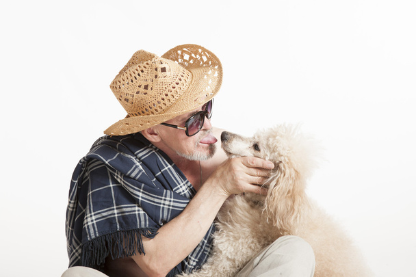 Man in a hat sitting with a poodle - Фото, зображення