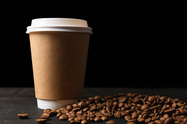 Бумажная чашка кофе и кофейных зерен на тёмном деревянном столе. Хорошо.
  - Фото, изображение