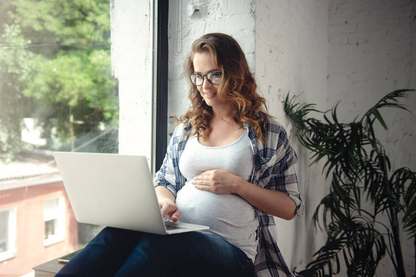 Terhes nő használata laptop számítógép otthoni munkavégzés - Fotó, kép