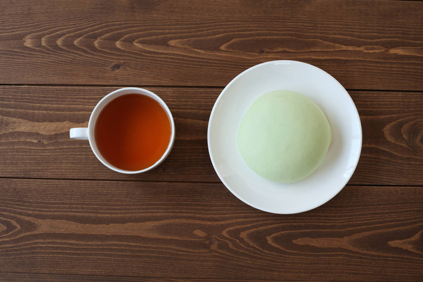 зеленая круглая сковорода дыни на тарелке с горячим чаем крупным планом, изолированным на деревянном столе
 - Фото, изображение