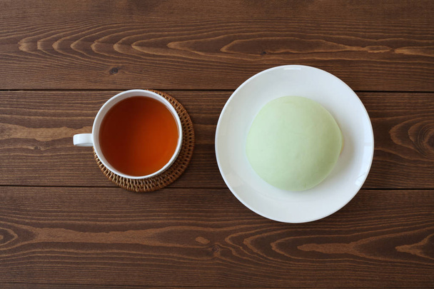 grüne runde Melonenpfanne auf Teller mit heißem Tee isoliert auf Holztisch - Foto, Bild