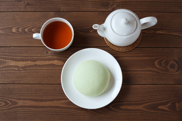 zielony okrągły patelnia na talerzu z gorącą herbatą na białym stole - Zdjęcie, obraz