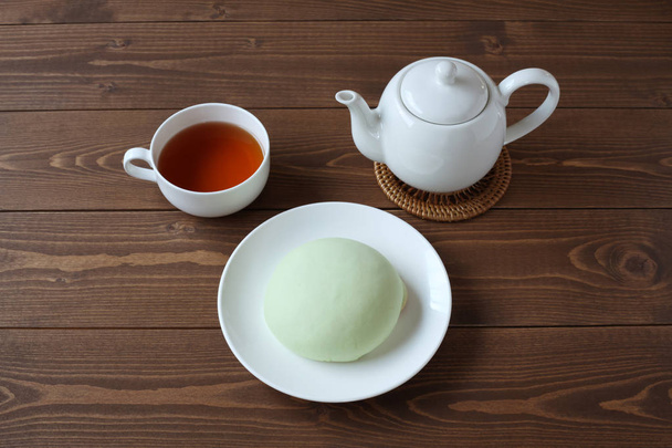 зеленая круглая сковорода дыни на тарелке с горячим чаем, изолированным на деревянном столе
 - Фото, изображение