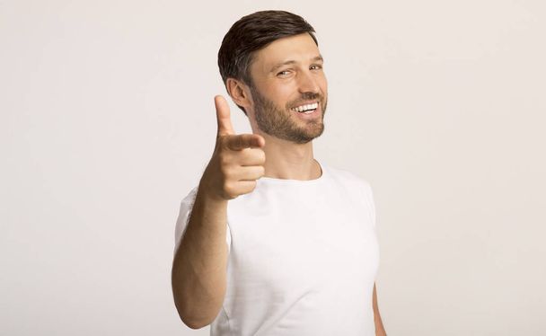 Guy pointing finger at camera standing on white background - Фото, изображение