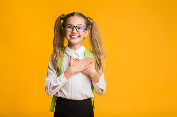 Благодарная школьница, улыбающаяся, кладущая руки на грудь, студийный снимок
 - Фото, изображение