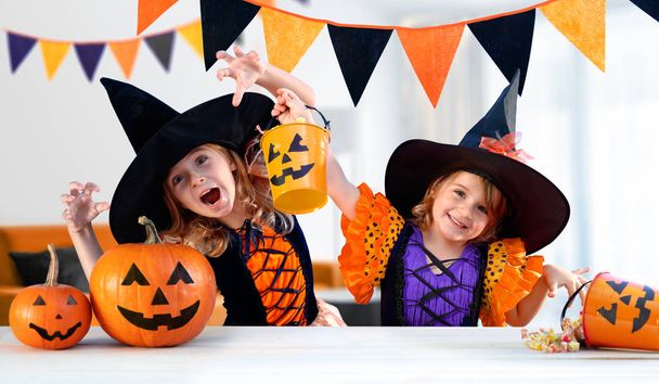 Happy Sisters With Carnival Costumes Indoors - Cheerful Children Play With Pumpkins And Candy - Foto, Bild