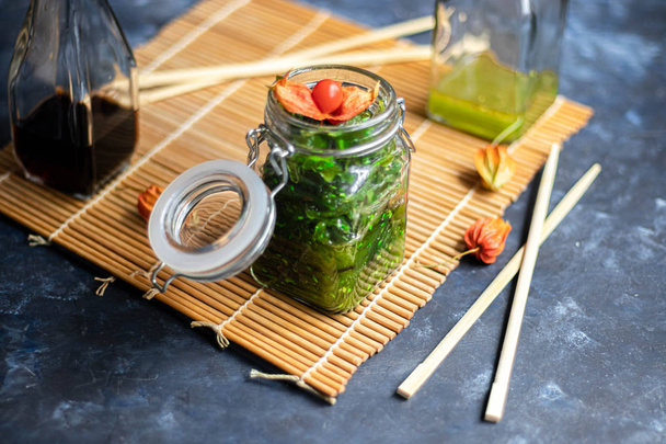 Seaweed Salad. Dietary and very beneficial for the thyroid gland. Dressed with vegetable oil, sprinkled with sesame seeds. Near wooden chopsticks.  - Photo, Image
