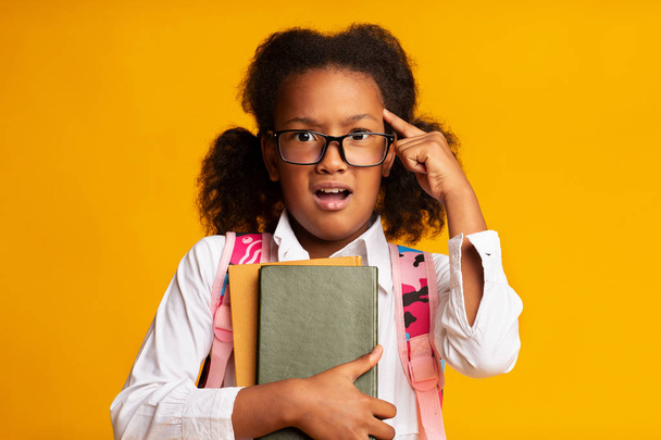 African American Schoolgirl Twisting Finger At Temple, Yellow Background - Photo, Image