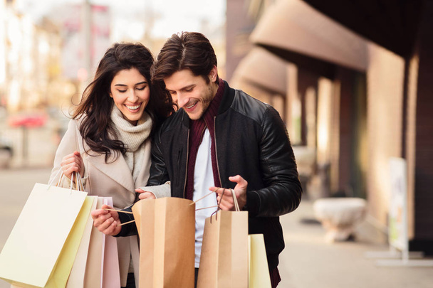 Excited couple looking into shopping bags outdoors - Photo, Image