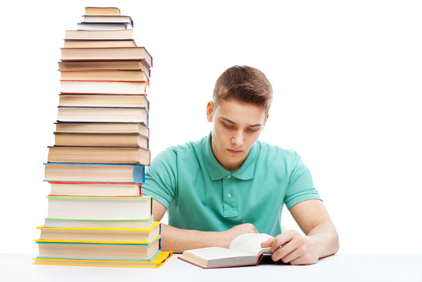 Student studying at a table with a stack of books - Фото, изображение