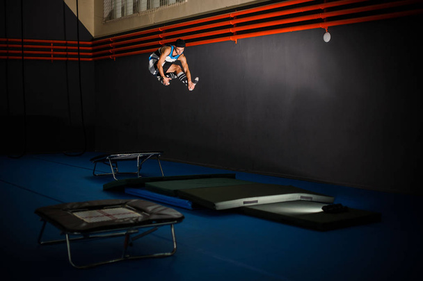 Man jumping from the little trampoline to the mat in the gym - Foto, afbeelding