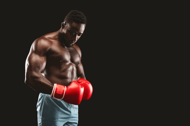 African fighter with red gloves on posing over black background - Photo, Image
