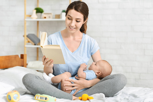 junge Mutter liest ihrem Neugeborenen Buch vor - Foto, Bild