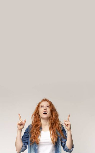 Great offer. Excited teenage girl pointing upwards at copy space - Foto, imagen