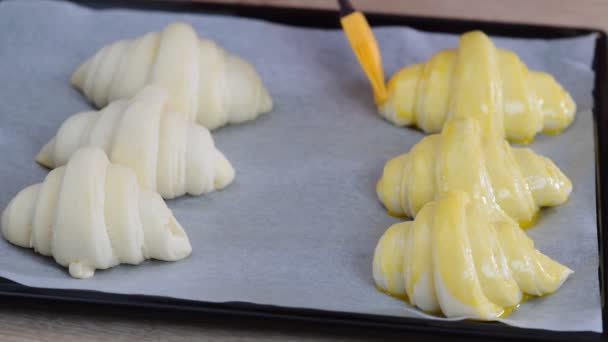Een bakker schilderij ei wassen op croissants die zal worden gebakken in een café. - Video