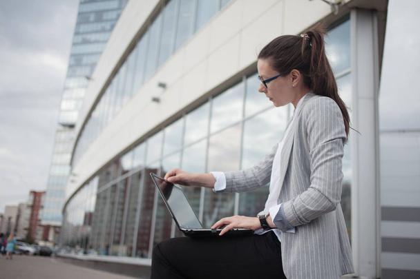Career growth and ambitions, concept. Young businesswoman with a laptop in her hands on the background of the business center. - Фото, зображення
