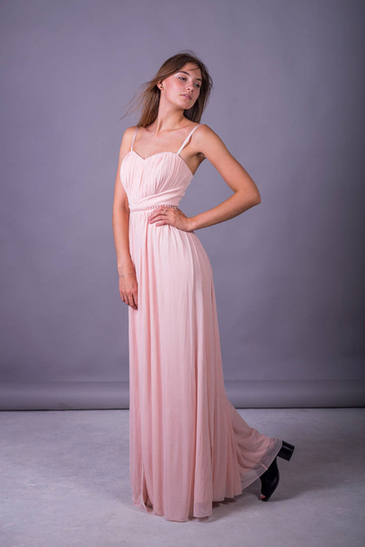 Young girl in a pink dress posing on a gray background. - Foto, Bild