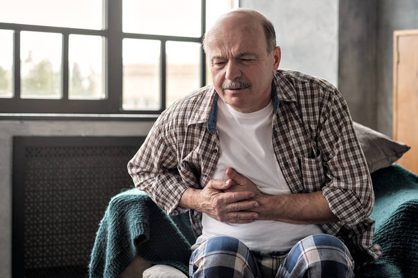 Hombre hispano mayor está teniendo pancreatitis o gastritis o colitis
. - Foto, Imagen