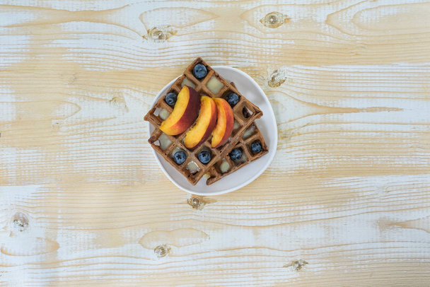 Gaufres belges au chocolat avec fruits et baies sur fond de bois blanc. Délicieux petit déjeuner. Vue du dessus
 - Photo, image