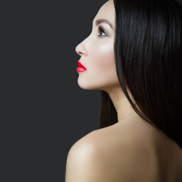 Νεαρή όμορφη γυναίκα με κόκκινο κραγιόν και τέλειο δέρμα. Σκούρα ίσια μακριά μαλλιά. - Φωτογραφία, εικόνα