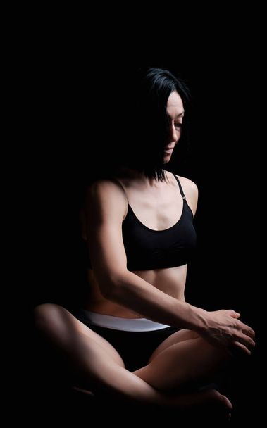joven chica de aspecto atlético con el pelo negro se sienta en un lotu
 - Foto, Imagen