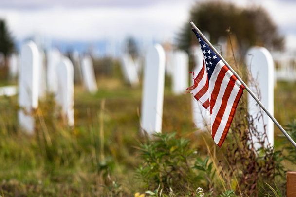 A wooden white grave mark with the United States flag in the Nome Cemetery, Alaska, shallow dof. - Photo, image
