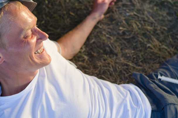 Addicted man laughing lying down on grass - Photo, Image